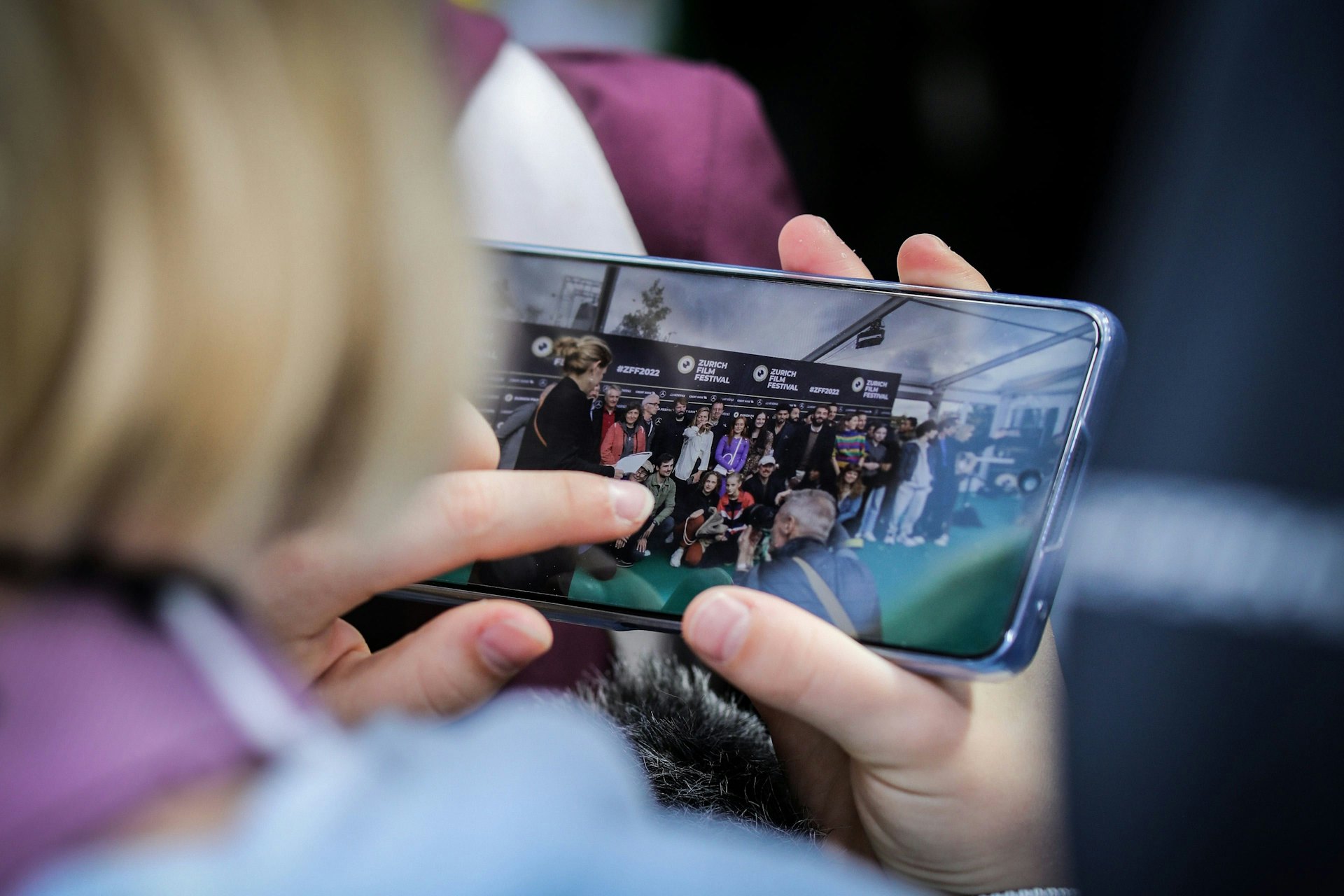 Frau hält Handy mit Foto vom Green Carpet