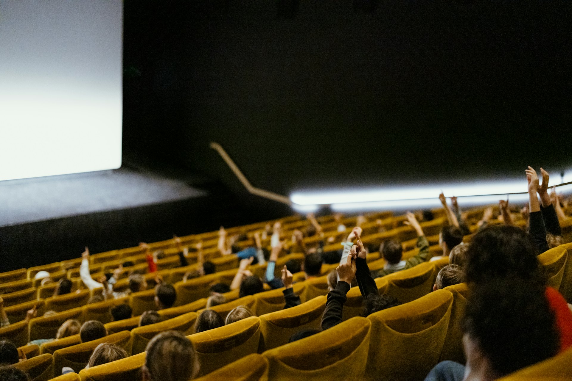 Children in a cinema auditorium. They are eating popcorns.